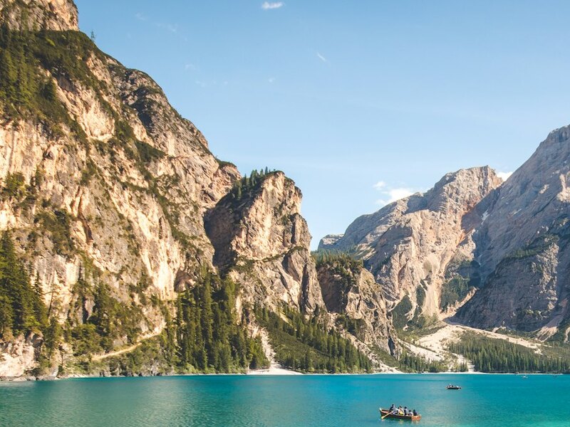 The same scene framed low and looking up — the cliff towers overhead and the boat sits small near the bottom.
